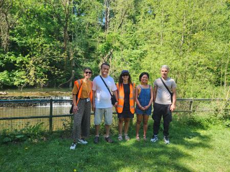a group of people standing near the river in the park 