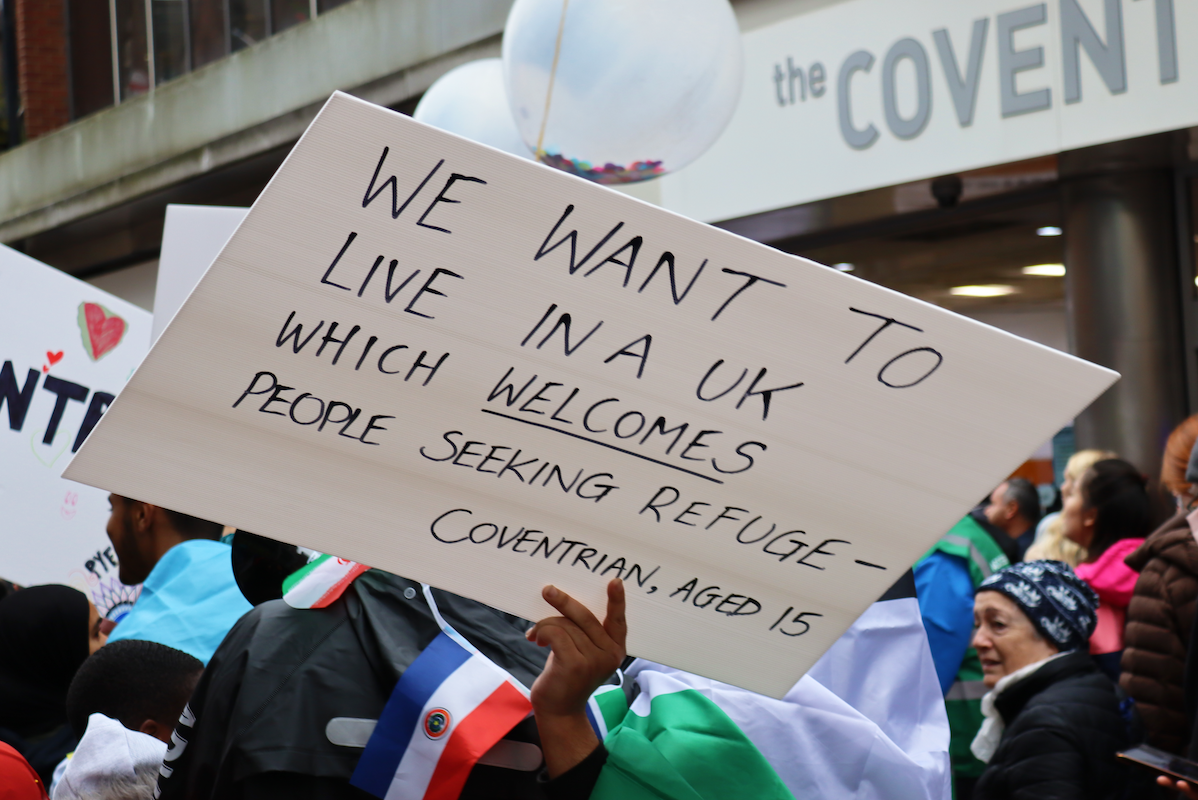 sign that says 'we want to live in a UK which welcomes people seeking refuge'