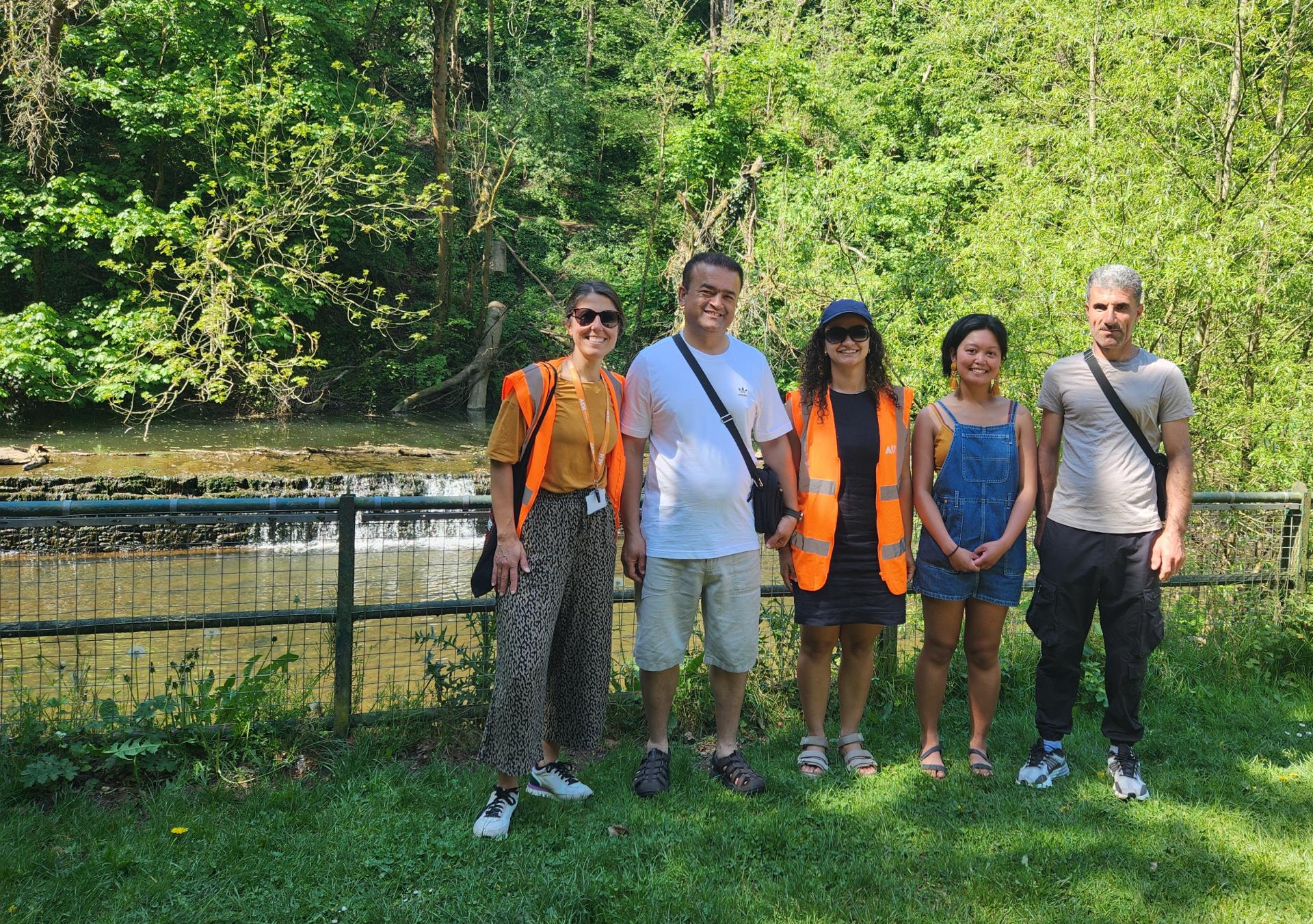 a group of people standing near the river in the park 
